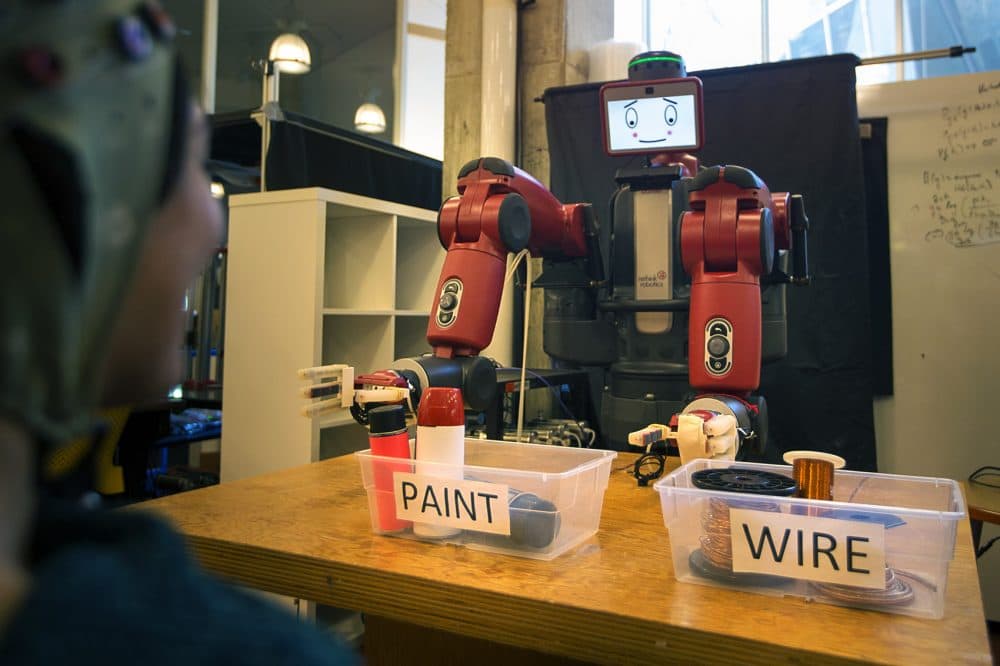 Researchers at MIT have created a system where humans can guide robots through simple binary activities with their brainwaves. Here, robot Baxter sorts items while a person observes. If the human notices a mistake, their brainwaves will automatically signal to the system that something has gone wrong and Baxter will attempt to correct himself. (Jesse Costa/WBUR)