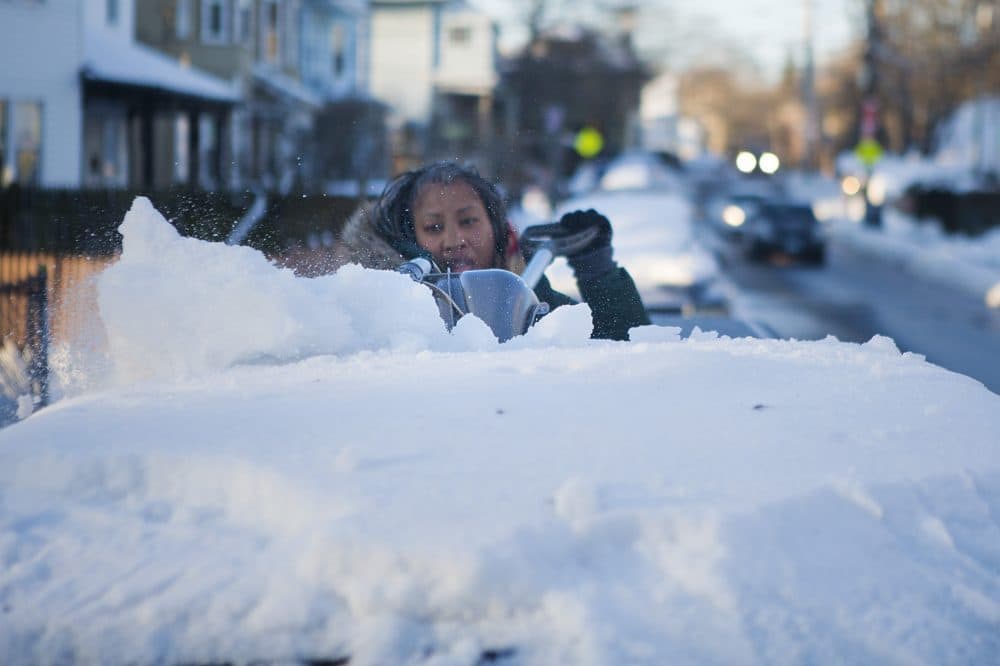 Natasha Fields uses a shovel to remove the ice from the roof of her car parked on Allston Street in Boston. (Jesse Costa/WBUR)