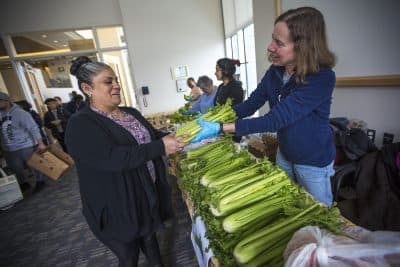 Blanca Gutierrez receives some celery from one of the volunteers at Charles River Community Health's free produce market in Brighton -- a partnership between the health center and the food bank. (Jesse Costa/WBUR)