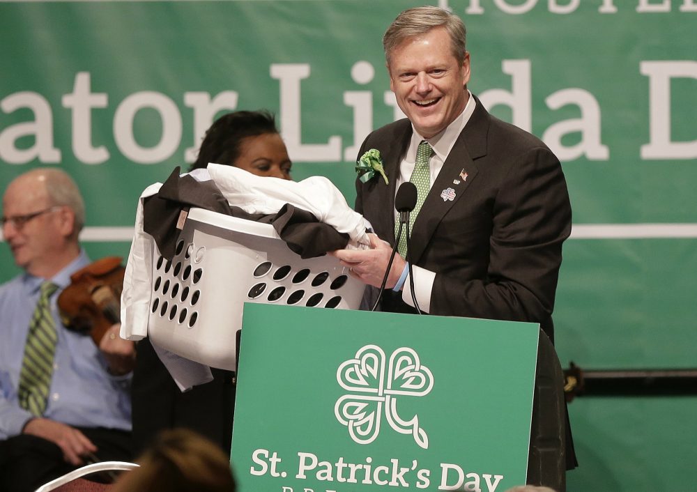 Gov. Charlie Baker carries a basket of laundry while making a joke referencing state Sen. Brian Joyce, D-Milton, at the annual St. Patrick's Day Breakfast, on March 20, 2016. (Steven Senne/AP)