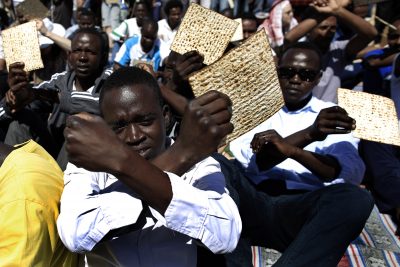African migrants hold matzo, unleavened bread traditionally eaten by Jews during the week-long Passover holiday, as they protest outside the Holot detention center, southern Israel, in April 2014. (Tsafrir Abayov/AP)