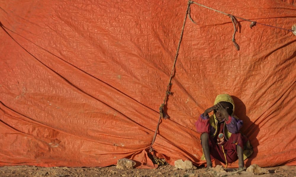 A young Somali boy sits outside his makeshift hut at a camp for people displaced from their homes elsewhere in the country by the drought, shortly after dawn in Qardho, Somalia on, March 9, 2017. (Ben Curtis/AP)