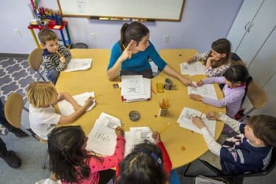 Students sit around Elina Starobinets as they do math worksheets at the Studio of Engaging Math in Brighton. (Jesse Costa/WBUR)