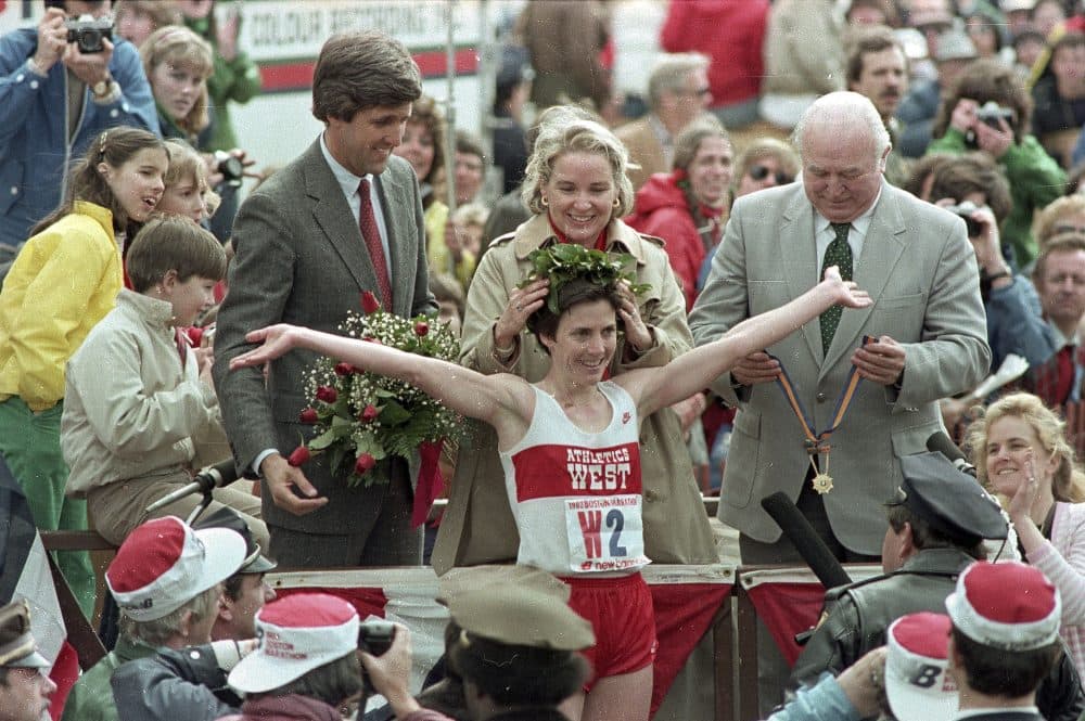 In this April 1983 file photo, Joan Benoit receives her laurel wreath and reacts to cheering crowds after winning the Boston Marathon in record time for the women's division. Lt. Gov. John Kerry, left in red tie, stands behind her. (AP file photo)