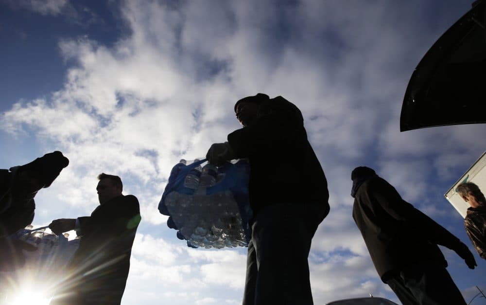 Midwest Food Bank workers and volunteers carry cases of water that was donated, Wednesday, Jan. 27, 2016, in Indianapolis. All of the water that was collected will be sent to Flint, Mich., where drinking water has been contaminated by lead. (Darron Cummings/AP)