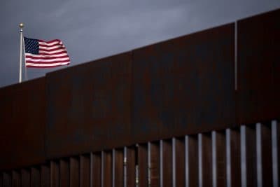 A U.S. flag flies near section of the border fence on the U.S.-Mexico border in Agua Prieta, Sonora, Mexico, in 2017. (Guillermo Arias/AFP/Getty Images)