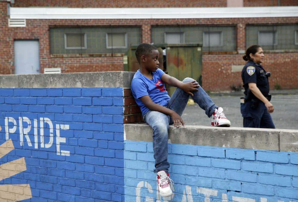Sessions' recent directive to his Department of Justice grants local police sole sway in how they interact with communities of color, without civilian input, writes Kevin C. Peterson. Pictured here: A boy sits on a wall as a member of the Baltimore Police Department walks by in the Penn North neighborhood of Baltimore, June 2016, near the site of unrest following the funeral of Freddie Gray. (Patrick Semansky/AP)