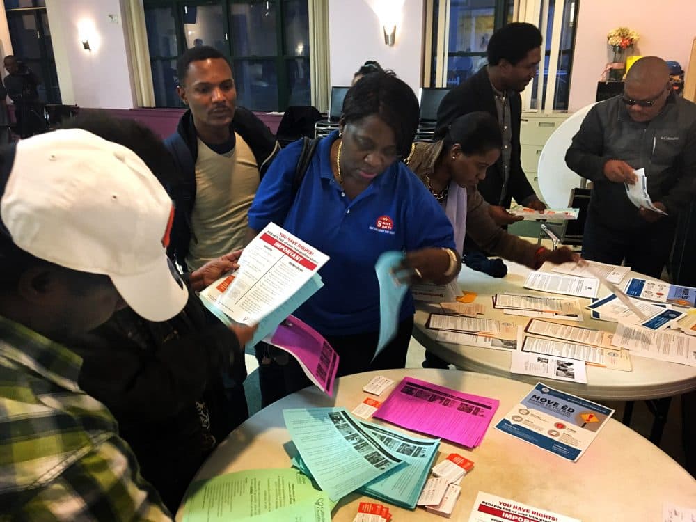 Attendees at a recent community forum collect handouts with information on immigration services. Many members of Boston’s Haitian community are worried about the fate of their Temporary Protected Status which enables them to live and work in the U.S. (Shannon Dooling/WBUR)