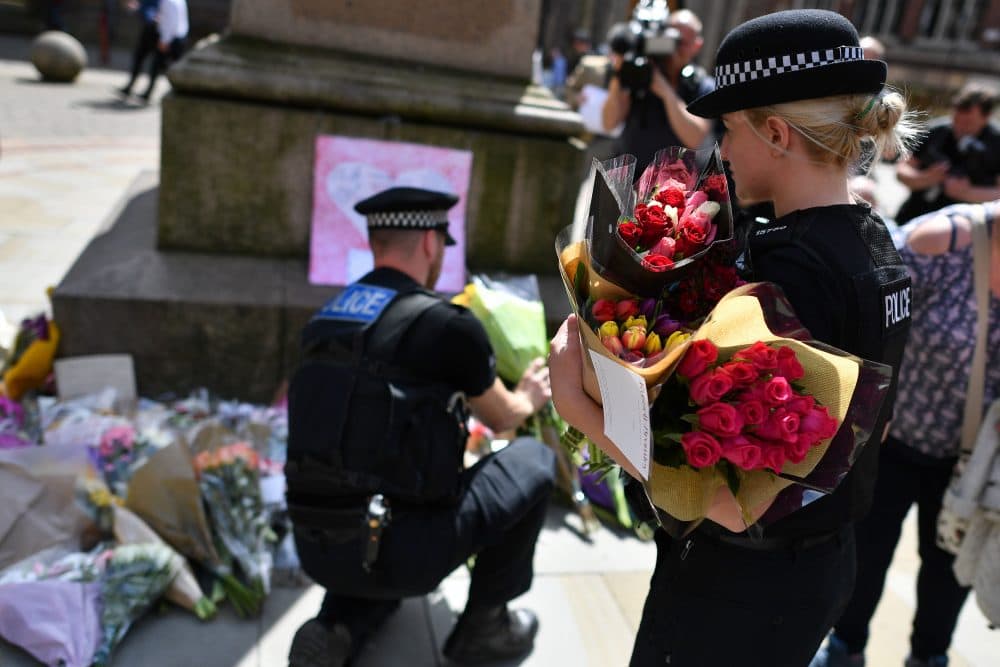 Police officers relocate floral tributes in St. Ann's Square in Manchester, northwest England, on May 23, 2017, laid as a mark of respect to those killed and injured following a deadly terror attack at a concert at Manchester Arena the night before. (Ben Stansall/AFP/Getty Images)
