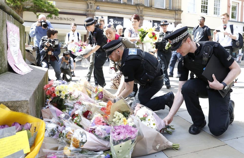 Police officers add to the flowers for the victims of the Monday night concert explosion, in St Ann's Square, Manchester. (Martin Rickett/PA via AP)
