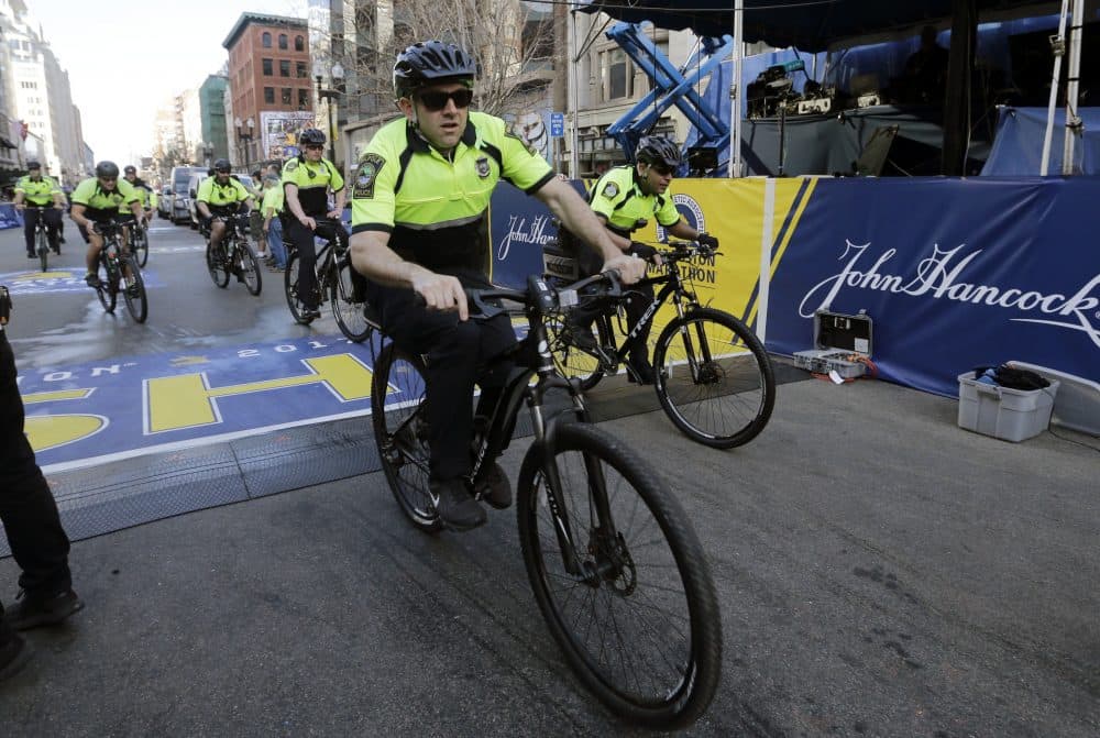 Boston police ride through the finish line area before the 121st Boston Marathon on Monday, April 17, 2017. The Police Department says covering special events and challenges with recruitment and retention have lead to an increase in overtime costs, but The Boston Globe analysis tells a different story. (Elise Amendola/AP)