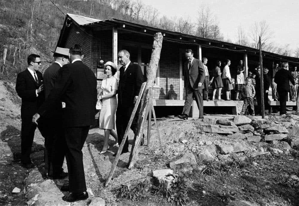 President Johnson and his wife are shown leaving the home of Tom Fletcher, father of eight, who told Johnson he'd been out of work for nearly two years. The president made a trip to eastern Kentucky to see conditions in the region. (AP)