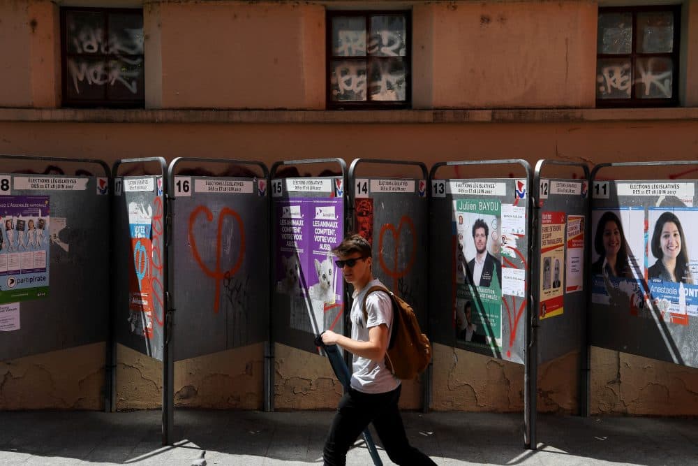 A teenager walks by election posters ahead of the first round of the upcoming legislative elections in Paris on June 9, 2017. (Christophe Archambault/AFP/Getty Images)