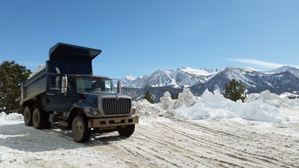 This March 2, 2017 photo provided by the California National Guard shows a Guard dump truck helping to clear huge snow drifts from the Eastern Sierra town of Mammoth Lakes, Calif. (California National Guard via AP)