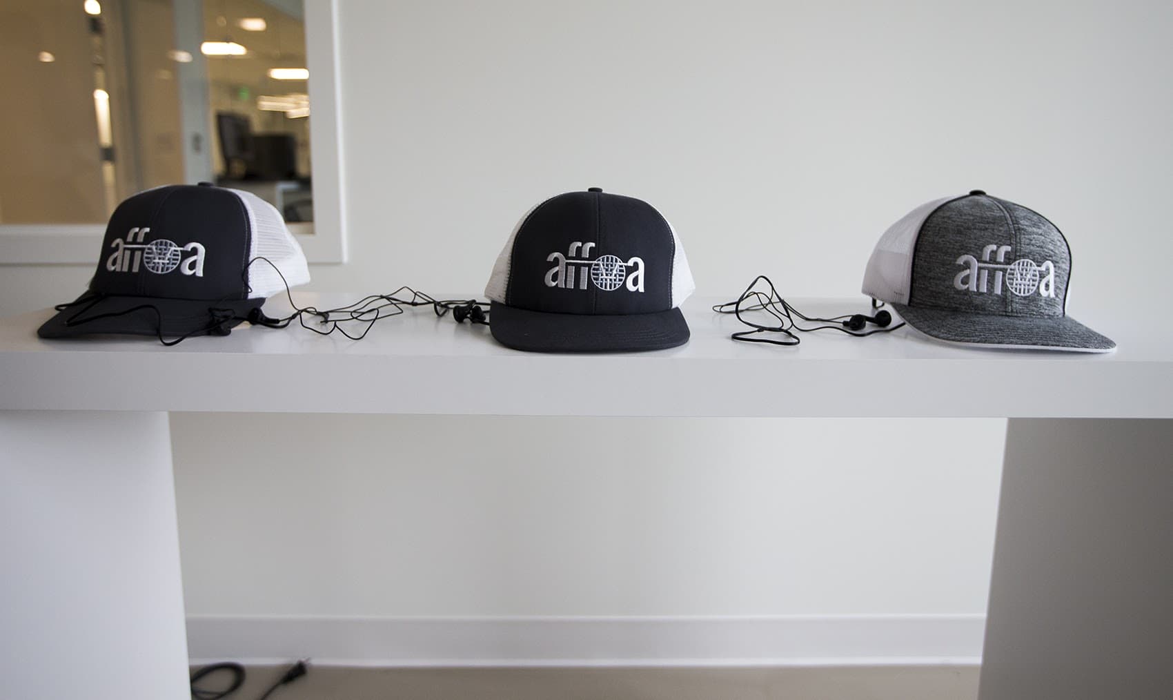 A display table with AFFOA trucker hats. When used with proper LED lighting, the hats can receive optical signals which is then converted to electrical signals to emit sound. (Jesse Costa/WBUR)