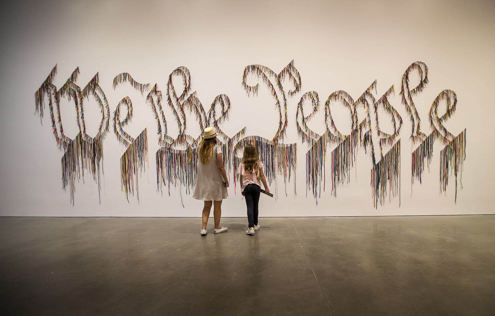 Visiting the ICA on vacation from Colombia, Maria Alejandra Garcia Velez and her daughter, Maria Jose Cortes Garcia, 9, approach the shoelace work by Nari Ward, &quot;We the People.&quot; (Jesse Costa/WBUR)
