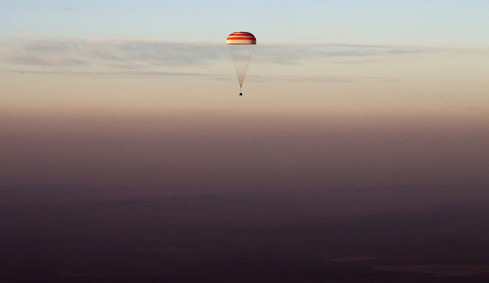 Perhaps aliens or robots would see enough potential in humanity to take us under their wing, writes Joelle Renstrom. And no travel ban or wall would stop them. Pictured: The Soyuz TMA-19M capsule carrying NASA's Jeff Williams, and two Russian cosmonauts descends beneath a parachute over Kazakhstan, in Sept., 2016 after a six-month mission aboard the International Space Station. (Maxim Shipenkov/AP)