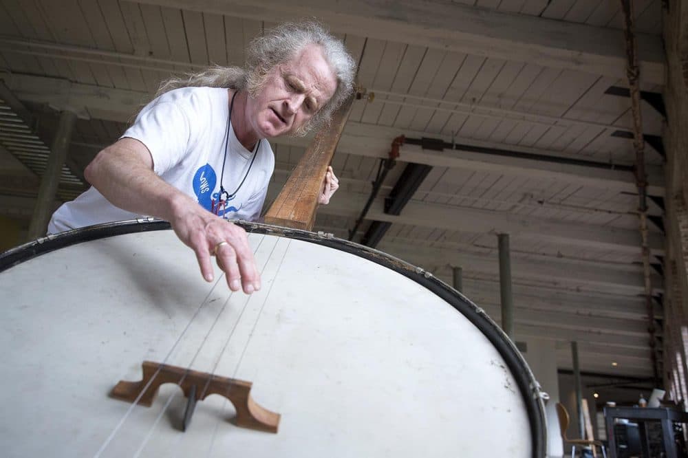 Musician Mark Stewart plays a giant banjo created by Gunnar Schonbeck. (Robin Lubbock/WBUR)
