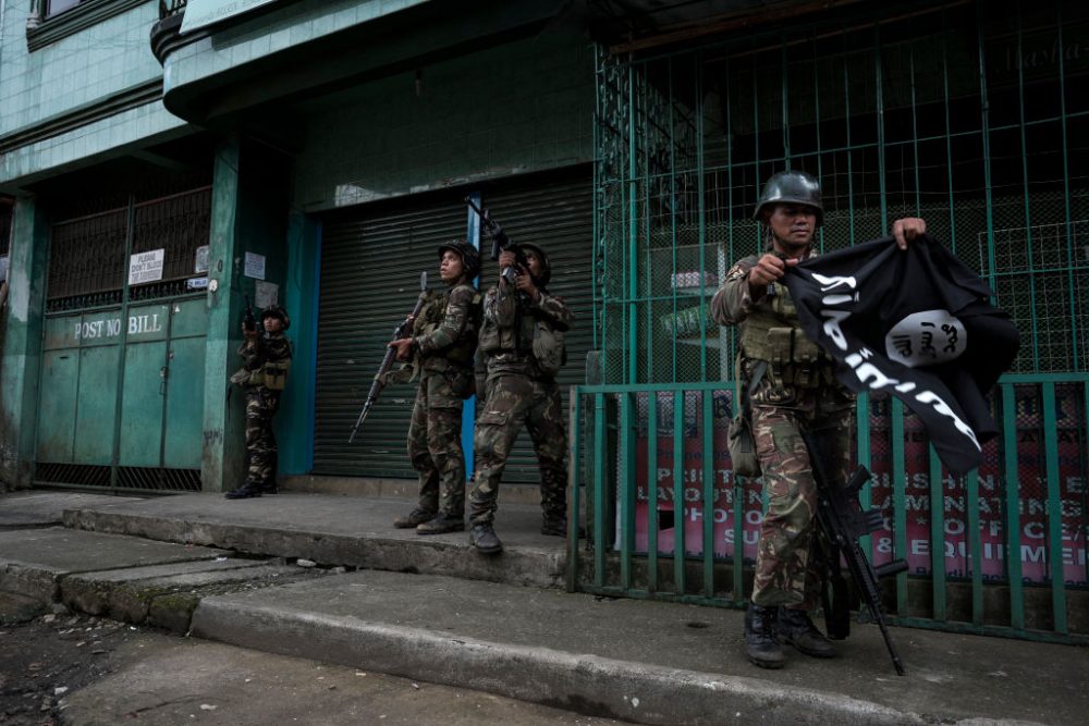 A soldier carrying a captured ISIS flag while clearing a city street of militants on May 26, 2017 in Marawi city, southern Philippines. (Jes Aznar/Getty Images)