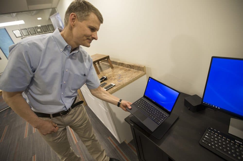 Morris Kesler, WiTricity's chief technology officer, places Dell's new wireless charging laptop on a charging pad. The computer charges through magnetic resonance technology developed at Watertown-based WiTricity. (Jesse Costa/WBUR)