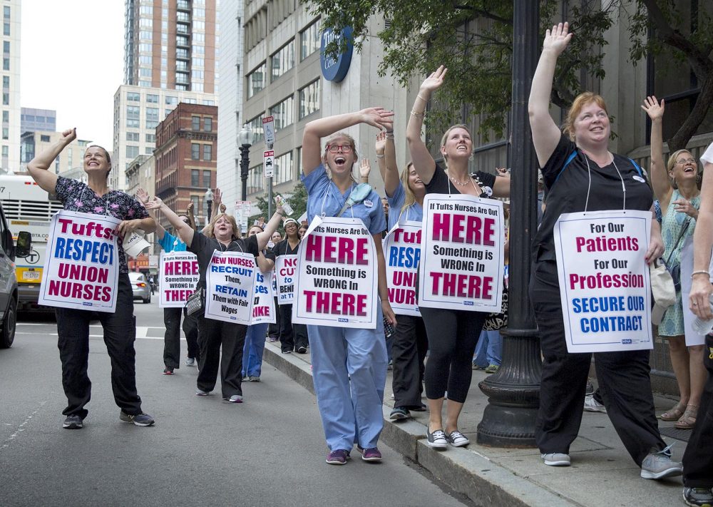 Nursing strike supporters on Washington Street wave at people inside Tufts Medical Center on Wednesday morning. (Robin Lubbock/WBUR)