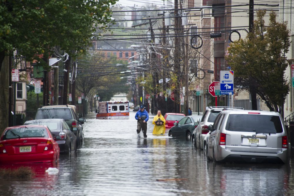 Residents walk through flood water and past a stalled ambulance in the aftermath of Superstorm Sandy on Tuesday, Oct. 30, 2012 in Hoboken, NJ. (Charles Sykes/AP)