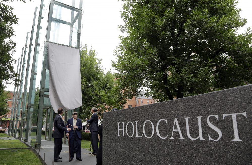 Holocaust survivor Steve Ross, center, founder of the New England Holocaust Memorial, is flanked by Boston Mayor Marty Walsh, left, and Massachusetts Gov. Charlie Baker Tuesday during a a rededication ceremony for the repaired New England Holocaust Memorial in Boston. One of the glass panes in the memorial was damaged by a vandal last month. (Elise Amendola/AP)