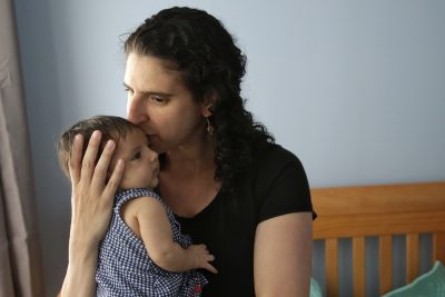 Elena Tenenbaum kisses her eight-week-old baby Zoe. Tenenbaum, a clinical psychology researcher, had her second daughter in April of 2017, and has been able to use Rhode Island's paid family leave program, which started in 2014 and covers four weeks of partial pay. (Steven Senne/AP)