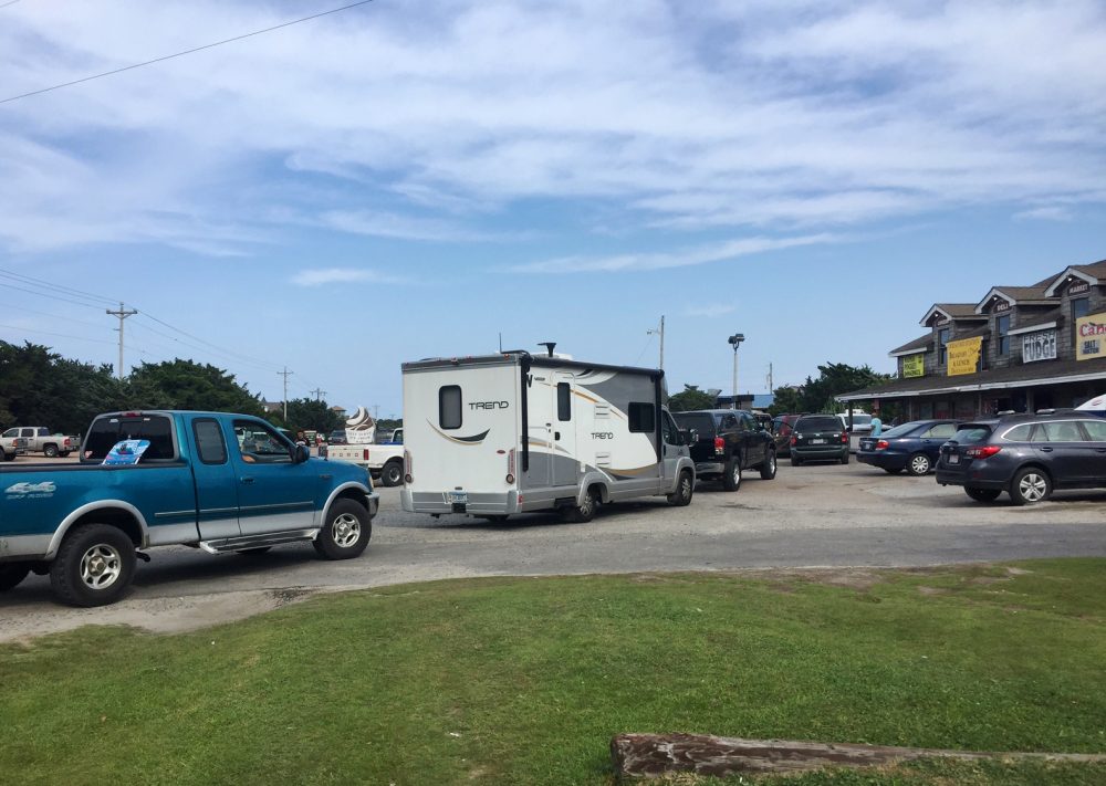 Vehicles line up at the a gas station on Thursday, July 27, 2017, on Ocracoke Island on North Carolina's Outer Banks, as visitors leave the island and residents fuel up. An estimated 10,000 tourists were ordered Thursday to evacuate the island after a construction company caused a power outage, leaving people stranded without air conditioning or places to eat. (C. Leinbach/Ocracoke Observer via AP)