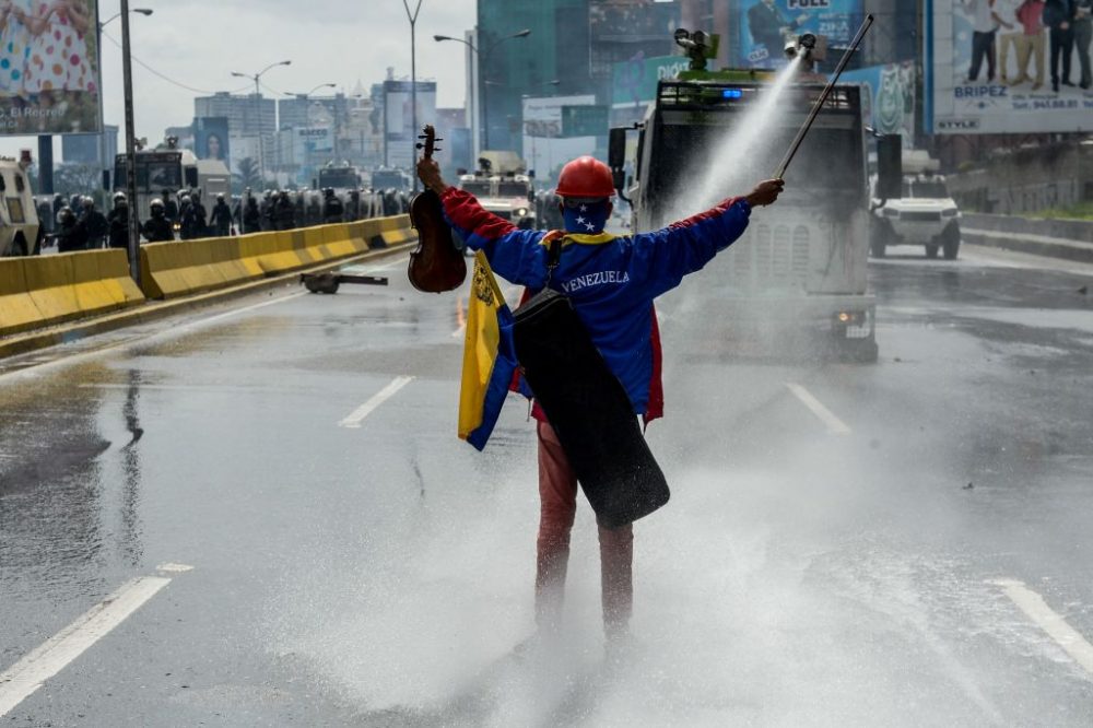 Opposition activist Wuilly Arteaga stands with a violin in front of an armoured vehicle of the riot police during a protest against President Nicolas Maduro in Caracas, on May 24, 2017. (Federico Parra/AFP/Getty Images)
