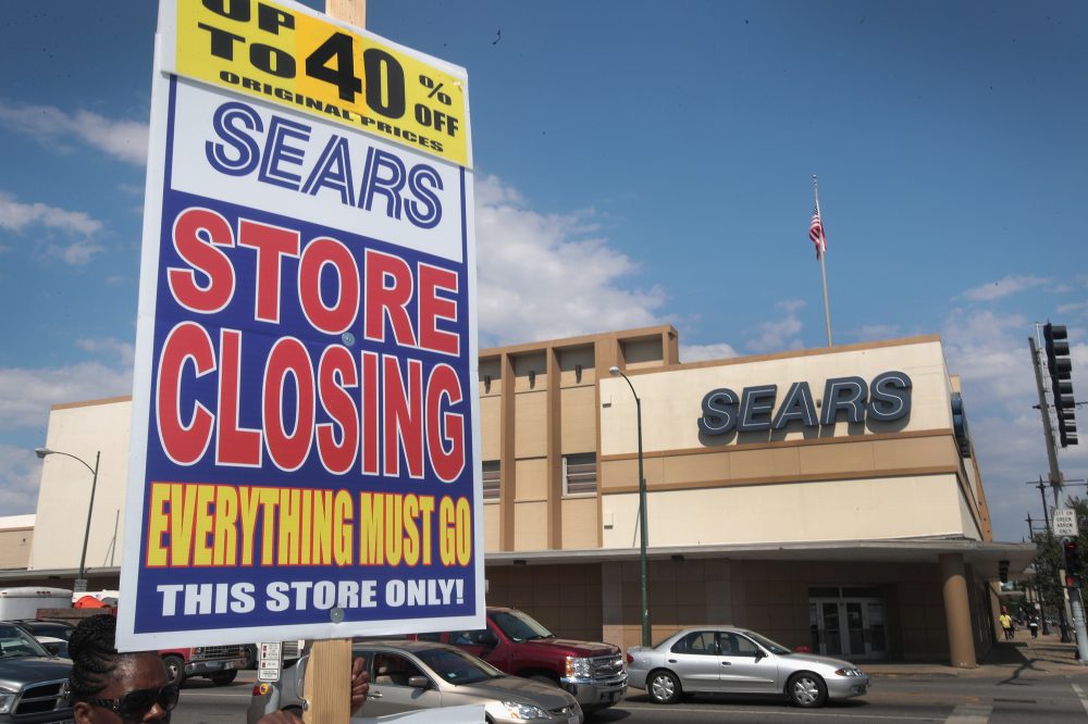 A worker holds a sign announcing a store-closing sale outside the 60-year-old Sears store in the Galewood neighborhood of Chicago on July 7, 2017. (Scott Olson/Getty Images)