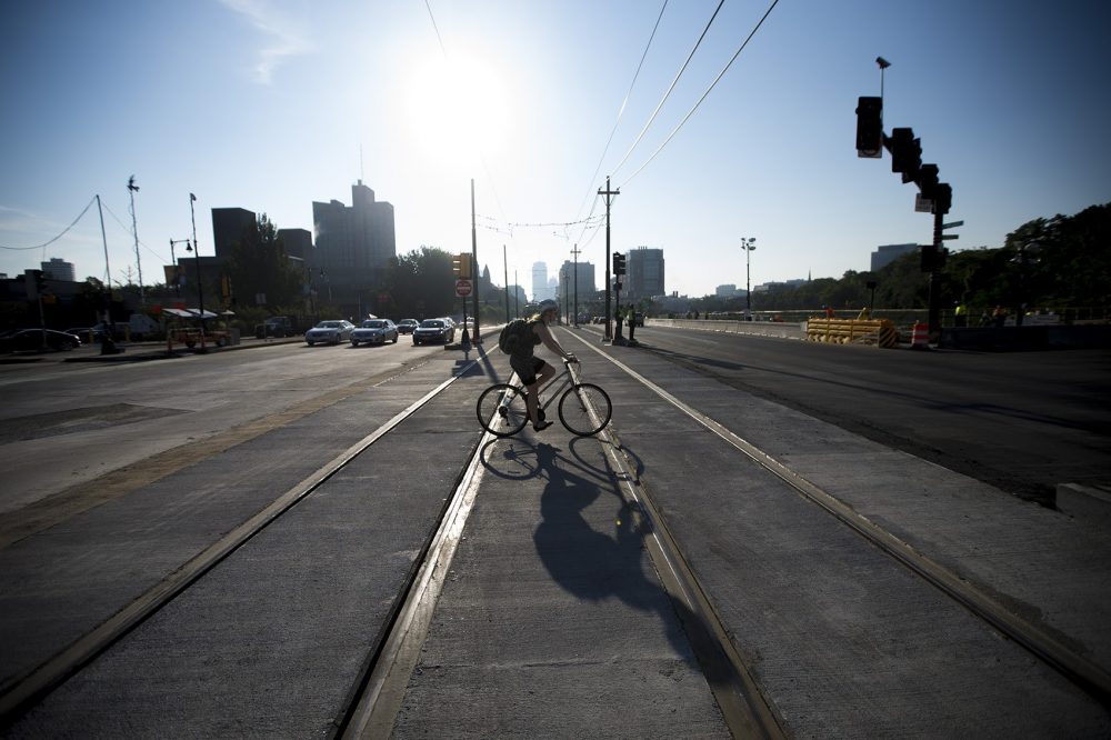 A cyclist crosses the Comm. Ave. Bridge Wednesday morning, the first day the road was reopened following three weeks of construction (Jesse Costa/WBUR)