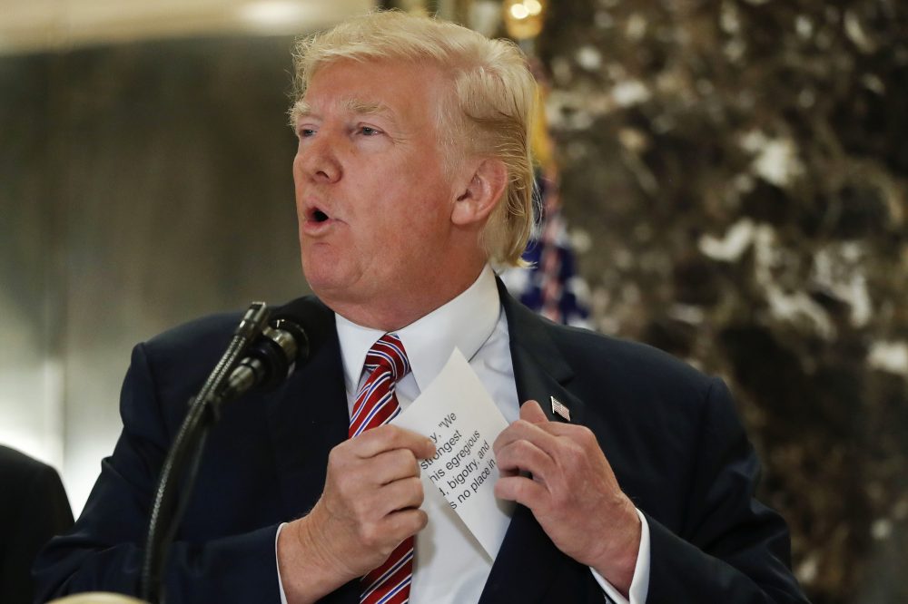President Trump reaches into his suit jacket to read a quote he made on Saturday regarding the events in Charlottesville, Va., as he speaks to the media in the lobby of Trump Tower in New York, Tuesday, Aug. 15, 2017. (Pablo Martinez Monsivais/AP)