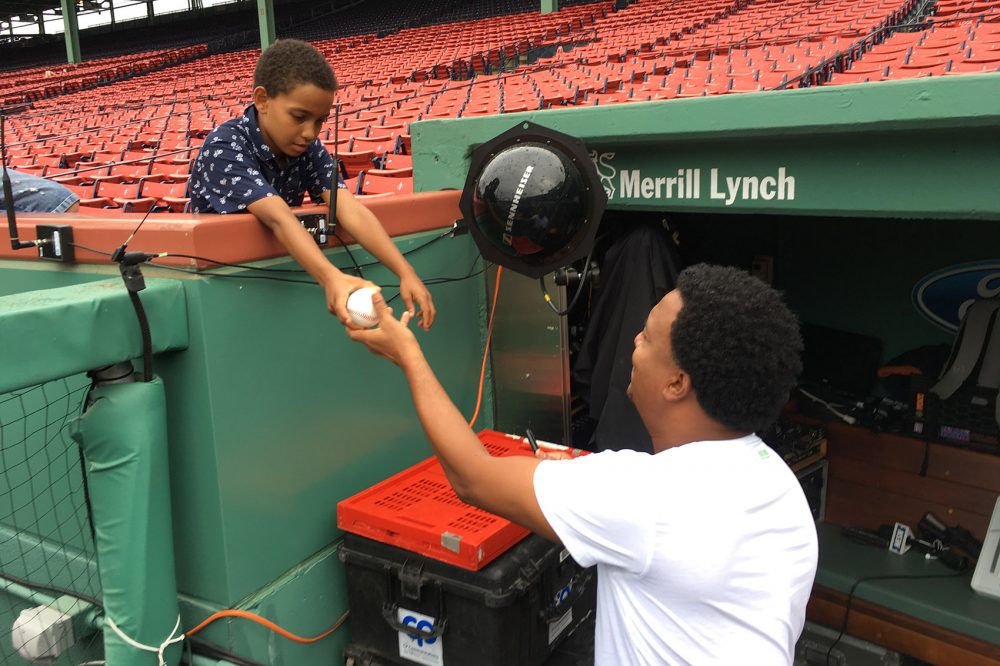 Former Boston Red Sox pitcher Pedro Martinez autographs a ball for a young fan at Fenway Park. (Lynn Jolicoeur/WBUR)