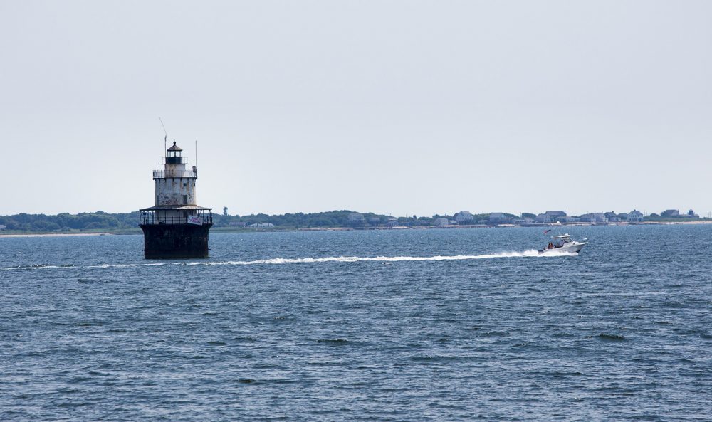 A boat speeds by the Butler Flats Lighthouse at the mouth of the Acushnet River at Buzzards Bay. (Jesse Costa/WBUR)