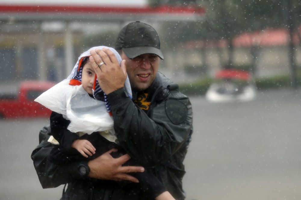 Sgt. Chad Watts, of the Louisiana Department of Wildlife and Fisheries, holds Madelyn Nguyen, 2, after he rescued her and her family by boat from floodwaters of Harvey in Houston on Monday. (Gerald Herbert/AP)