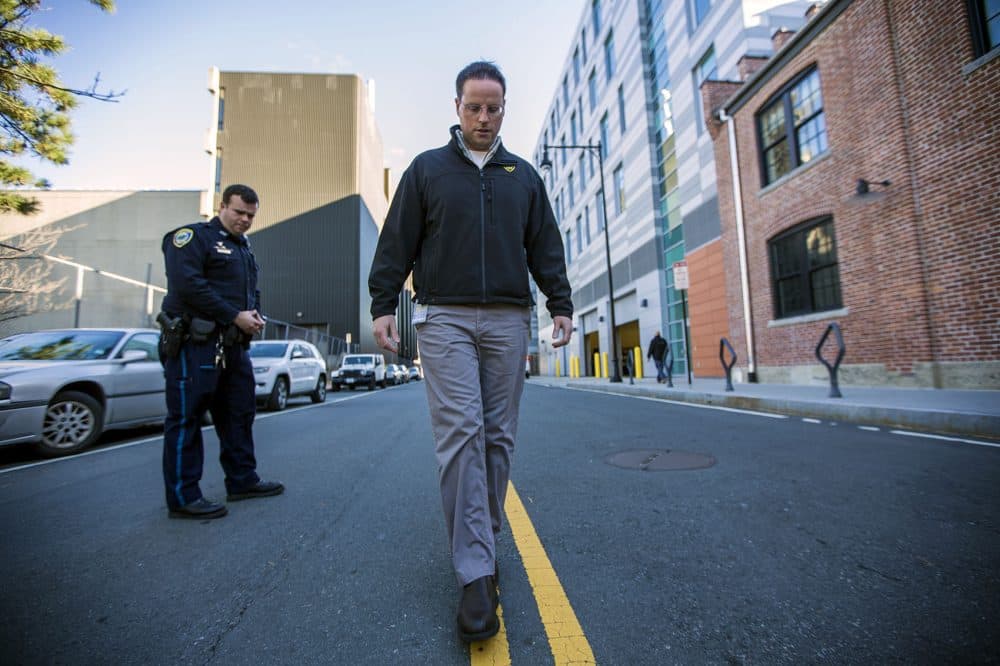The state says it will work to increase the number of officers trained in specific programs to detect drug impairment in drivers, like Cambridge police officer Jason Callinan, a drug recognition expert, or DRE. Here, Callinan, left, and Jeremy Warnick, a spokesman for the department, demonstrate the walk and turn line test down the center of Rogers Street last year. (Jesse Costa/WBUR)