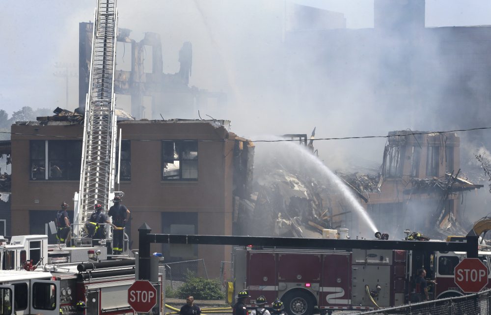 Firefighters pour water on the destroyed remains of an under-construction apartment complex, Sunday, July 23, in Waltham. Investigators say the fire was intentionally set. (Steven Senne/AP)