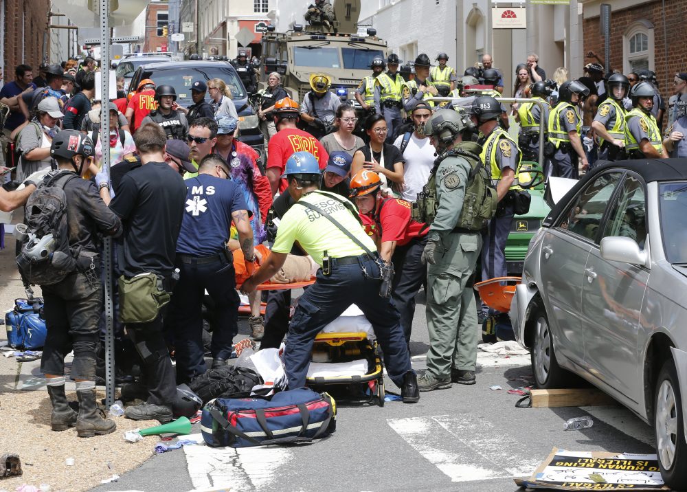 Rescue personnel help injured people after a car ran into a large group of protesters after an white nationalist rally in Charlottesville, Va., Saturday, Aug. 12, 2017. The nationalists were holding the rally to protest plans by the city of Charlottesville to remove a statue of Confederate Gen. Robert E. Lee. There were several hundred protesters marching in a long line when the car drove into a group of them. (AP Photo/Steve Helber)