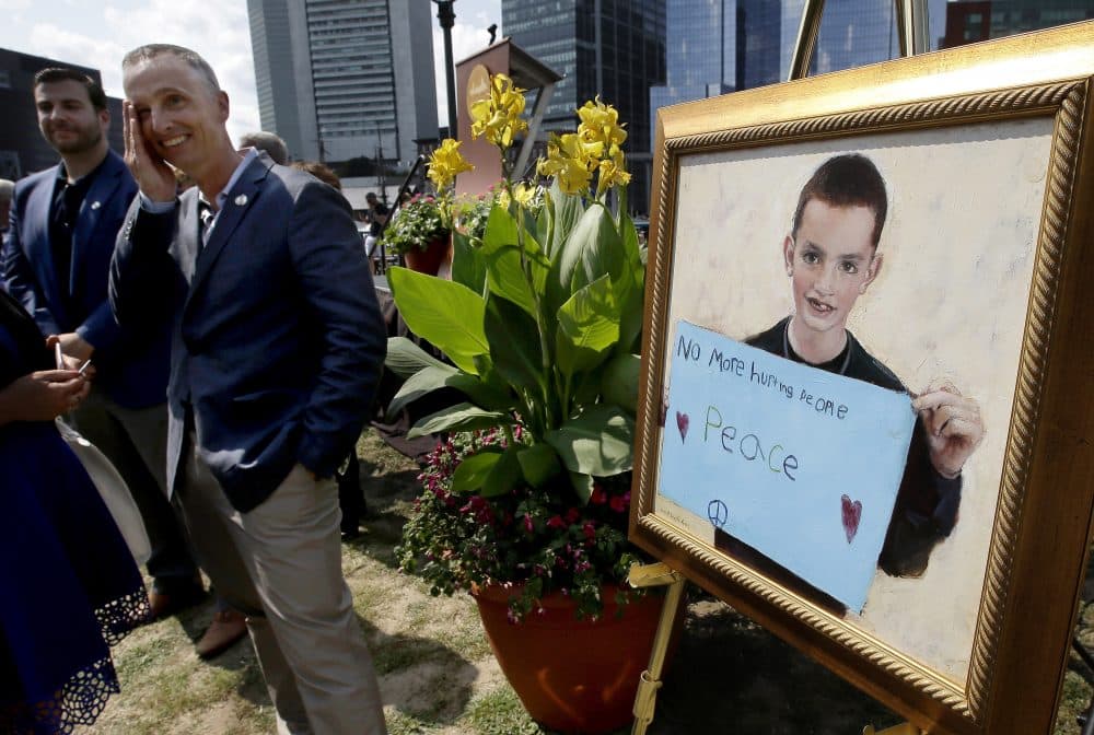 Bill Richard, father of Boston Marathon bombing victim Martin Richard, brings his hand to his face while standing next to a painting of Martin at the conclusion of groundbreaking ceremonies for a park named after his late son, Wednesday in Boston. (Steven Senne/AP)