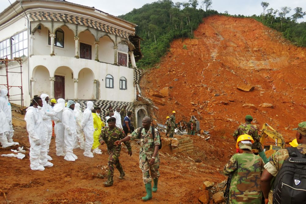 Search and rescue team members and soldiers operate near a mudslide site and damaged building near Freetown on Aug. 15, 2017, after landslides struck the capital of the west African state of Sierra Leone. (Mohamed Saidu BAH/AFP/Getty Images)