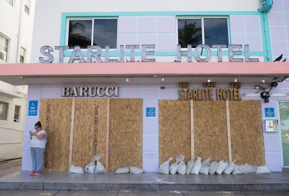 A woman uses her cellphone alongside a boarded-up hotel following mandatory evacuation orders in Miami Beach, Florida, Sept. 7, 2017, ahead of Hurricane Irma. (Saul Loeb/AFP/Getty Images)