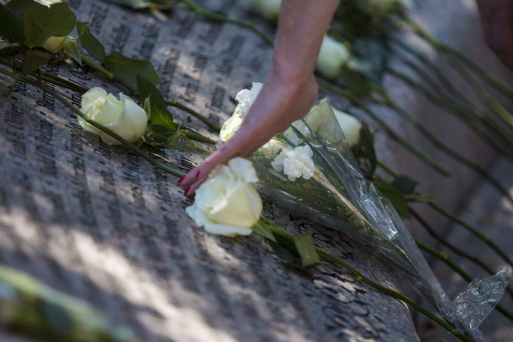 A visitor touches a name on the 9/11 Memorial in the Public Garden. (Jesse Costa/WBUR)