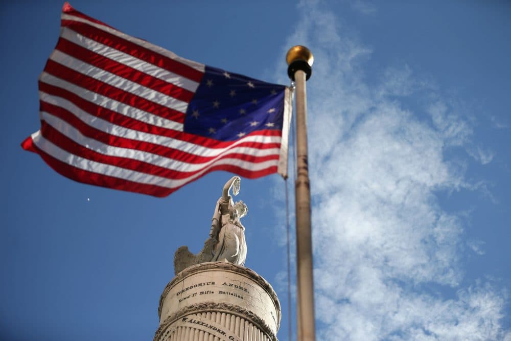 A U.S. flag with 15 stripes and 15 stars, like the one that was flown Fort McHenry during the War of 1812, frames the Battle Monument during the Star Spangled Spectacular Sept. 12, 2014, in Baltimore. (Chip Somodevilla/Getty Images)
