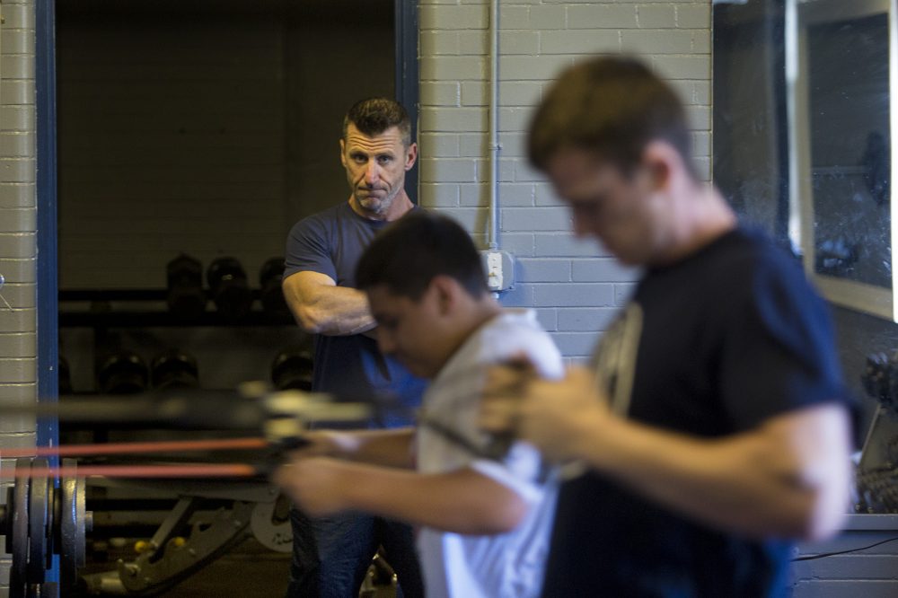 Marine veteran Jeff Buckley keeps an eye on workout participants doing band pulls in the basement of All Dorchester Sports and Leadership at Town Field. (Jesse Costa/WBUR)