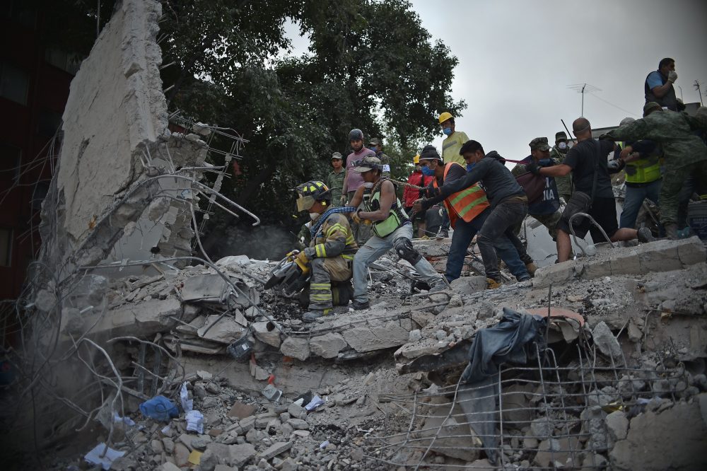 Rescuers, firefighters, policemen, soldiers and volunteers remove rubble and debris from a flattened building in search of survivors after a powerful earthquake in Mexico City on Sept. 19, 2017. (Yuri Cortez/AFP/Getty Images)