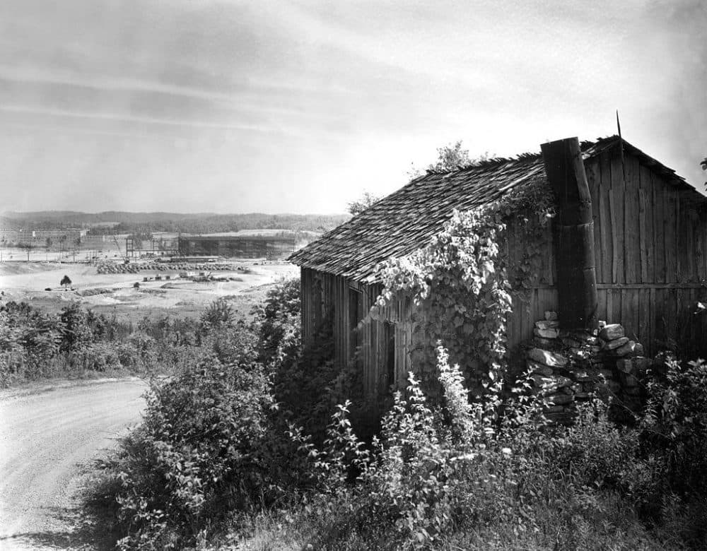 In 1942, original houses in the Oak Ridge area started to be replaced by construction for the war effort. In the background of this photo, K-25 is being built — which used the gaseous diffusion method to enrich uranium. (Ed Wescott/U.S. Department of Energy)