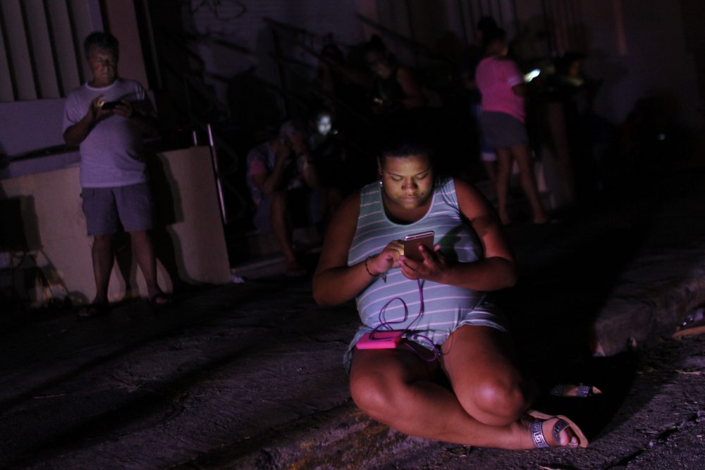A woman checks her cellphone next to a road at night in one of the few places with cell signal access in San Juan, Puerto Rico, on Sept. 25, 2017. (Ricardo Arduengo/AFP/Getty Images)