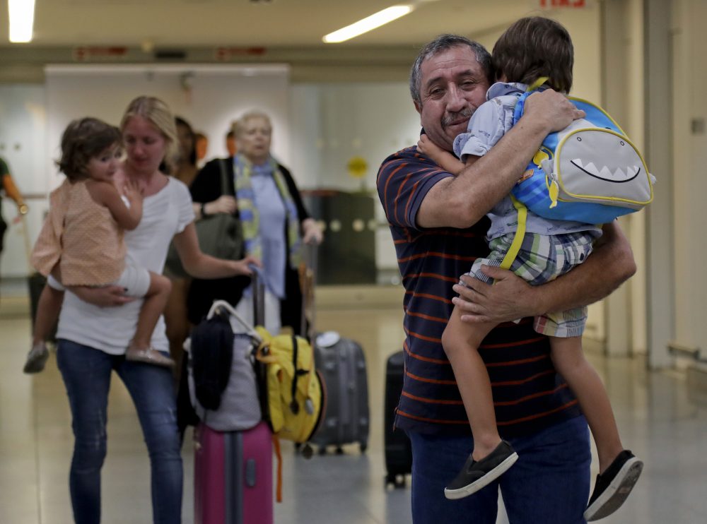 Juan Rojas, right, of Queens, hugs his 4-year-old grandson Elias Rojas, as his daughter-in-law Cori Rojas, left, carries her daughter Lilly, 3, through the terminal at JFK airport after Cori arrived on a flight from San Juan, Puerto Rico, Tuesday, Sept. 26, 2017, in New York. (Julie Jacobson/AP)