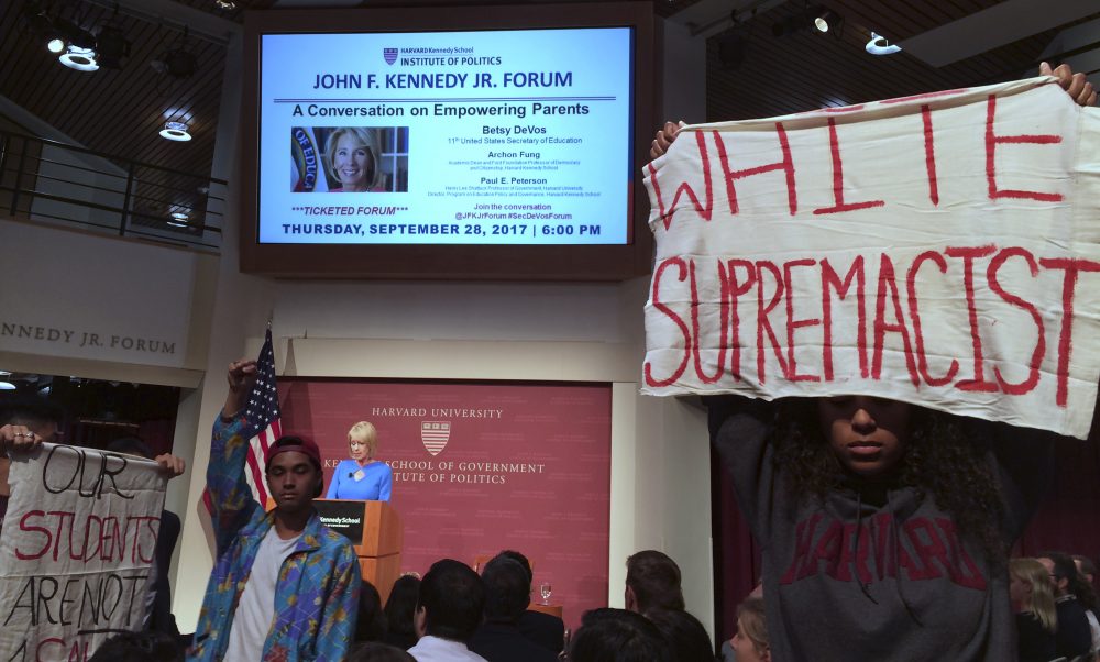 Protesters stand and hold signs and demonstrate during a speech by Education Secretary Betsy DeVos at Harvard University's Kennedy School of Government on Thursday. (Maria Danilova/AP)